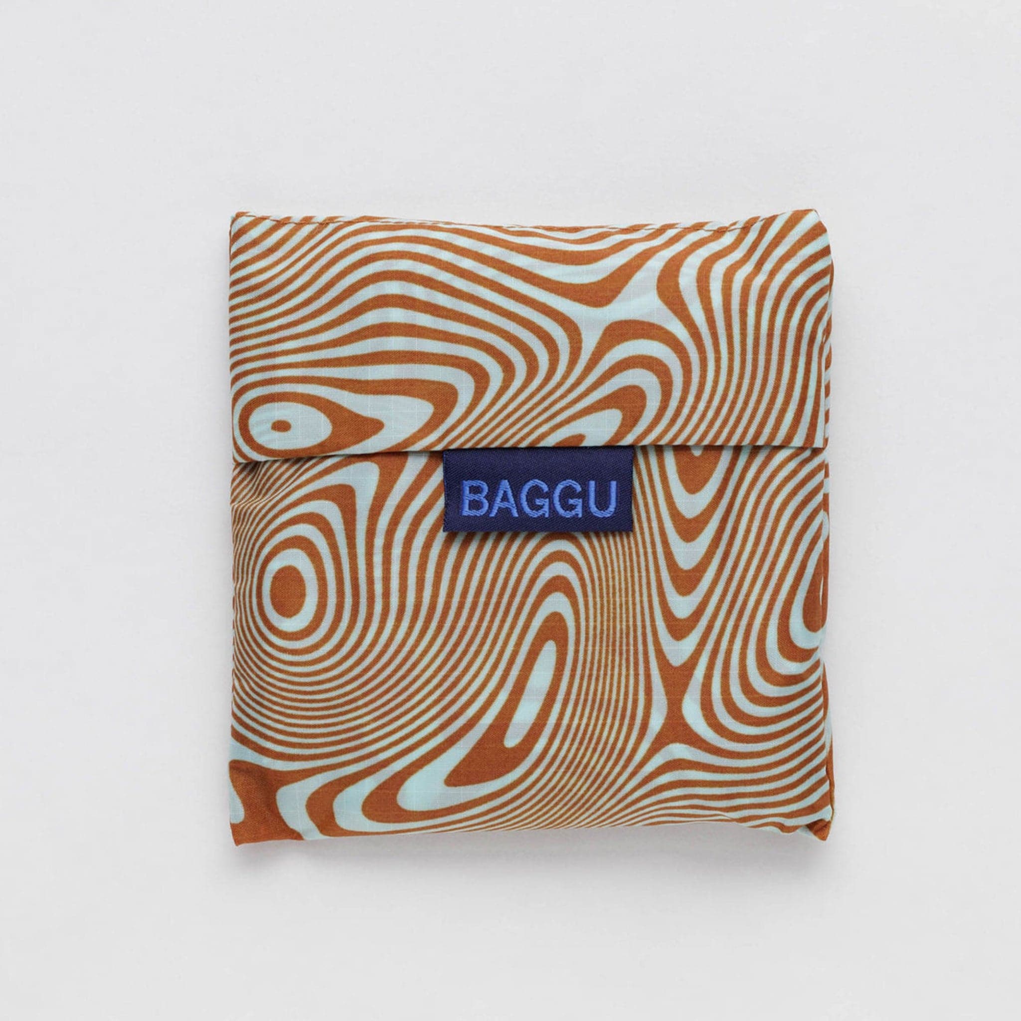 A nylon bag with an orange and cream wavy swirl pattern all over photographed here folded in a pouch. 