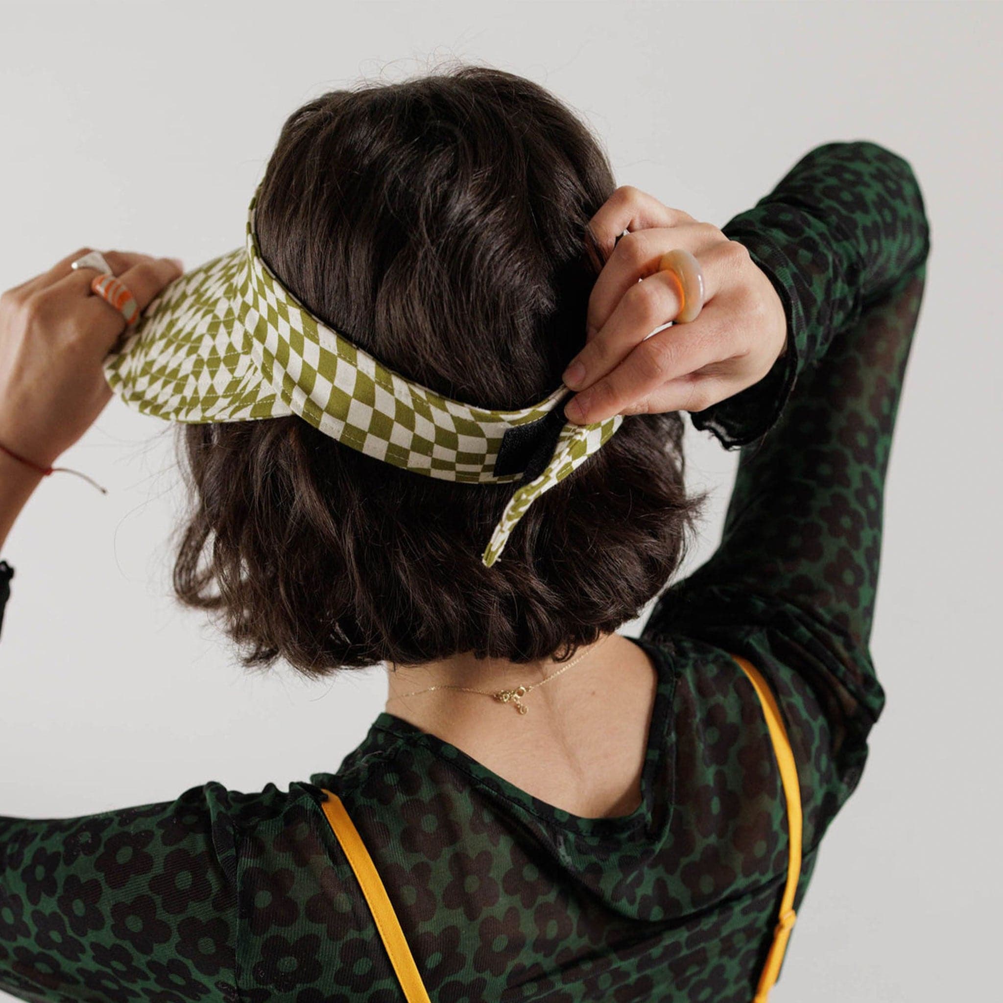 The green and white wavy checkered visor is shown here on a model displaying the adjustable strap on the back.