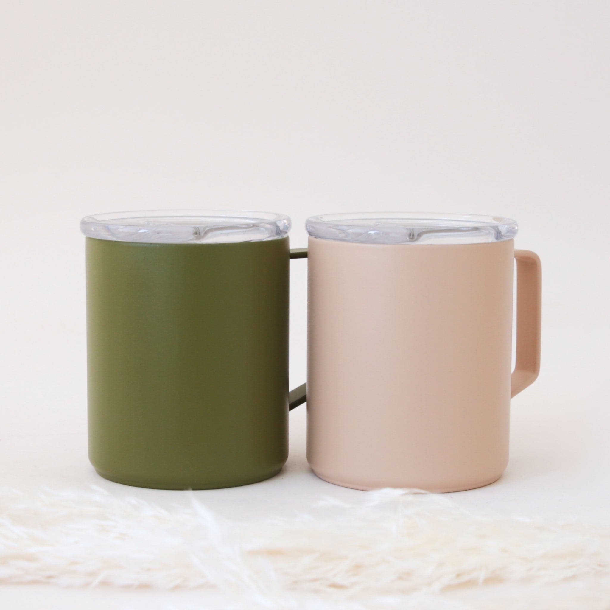 A light pink travel mug with a handle and a snap on lid.