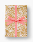 Gold wrapping paper with white leaf and flower designs.