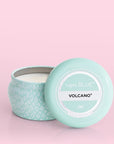 A small blue tin candle with white wax and a white diamond repeating pattern on the outside of the tin. Comes with a matching blue lid that reads, "Capri Blue Volcano".