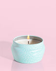 A small blue tin candle with white wax and a white diamond repeating pattern on the outside of the tin. Comes with a matching blue lid that reads, "Capri Blue Volcano".