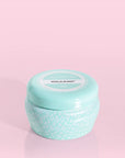 A small blue tin candle with white wax and a white diamond repeating pattern on the outside of the tin. Comes with a matching blue lid that reads, "Capri Blue Volcano".