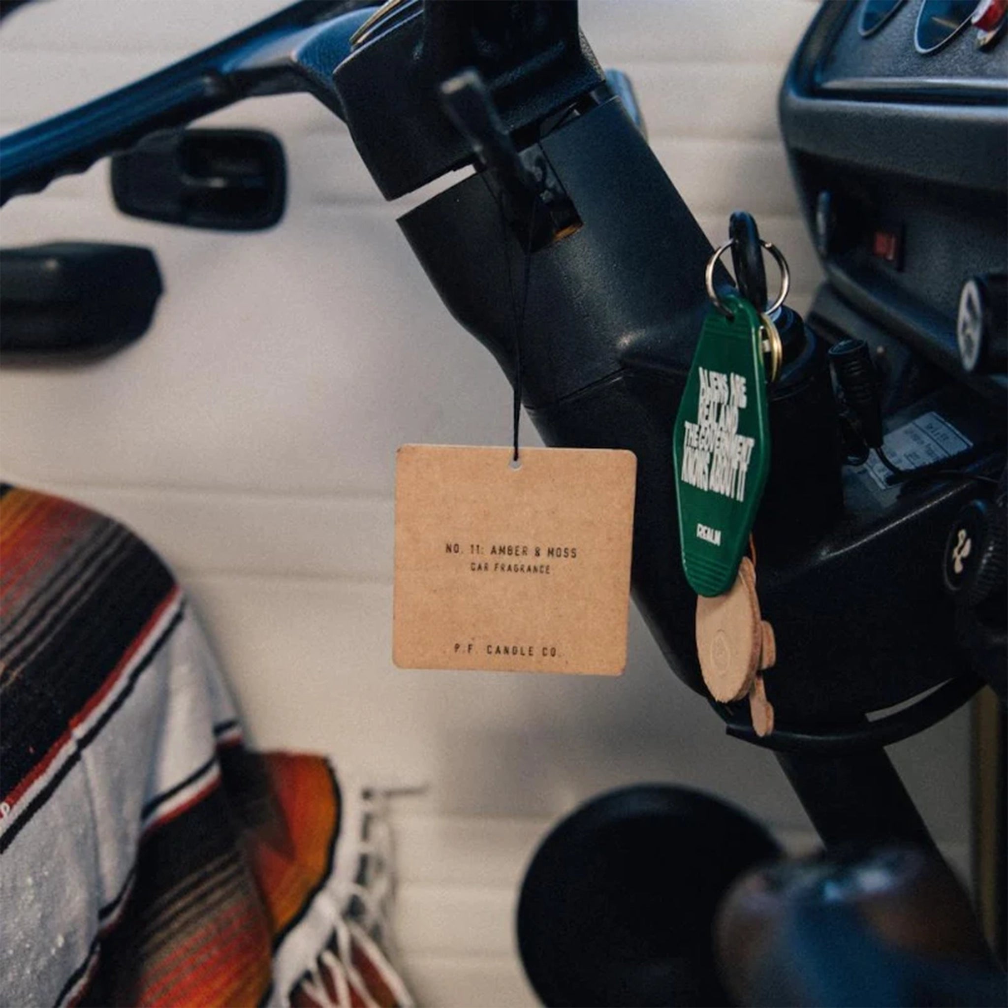 The square cardboard car fragrance hanging from the steering wheel of a car.
