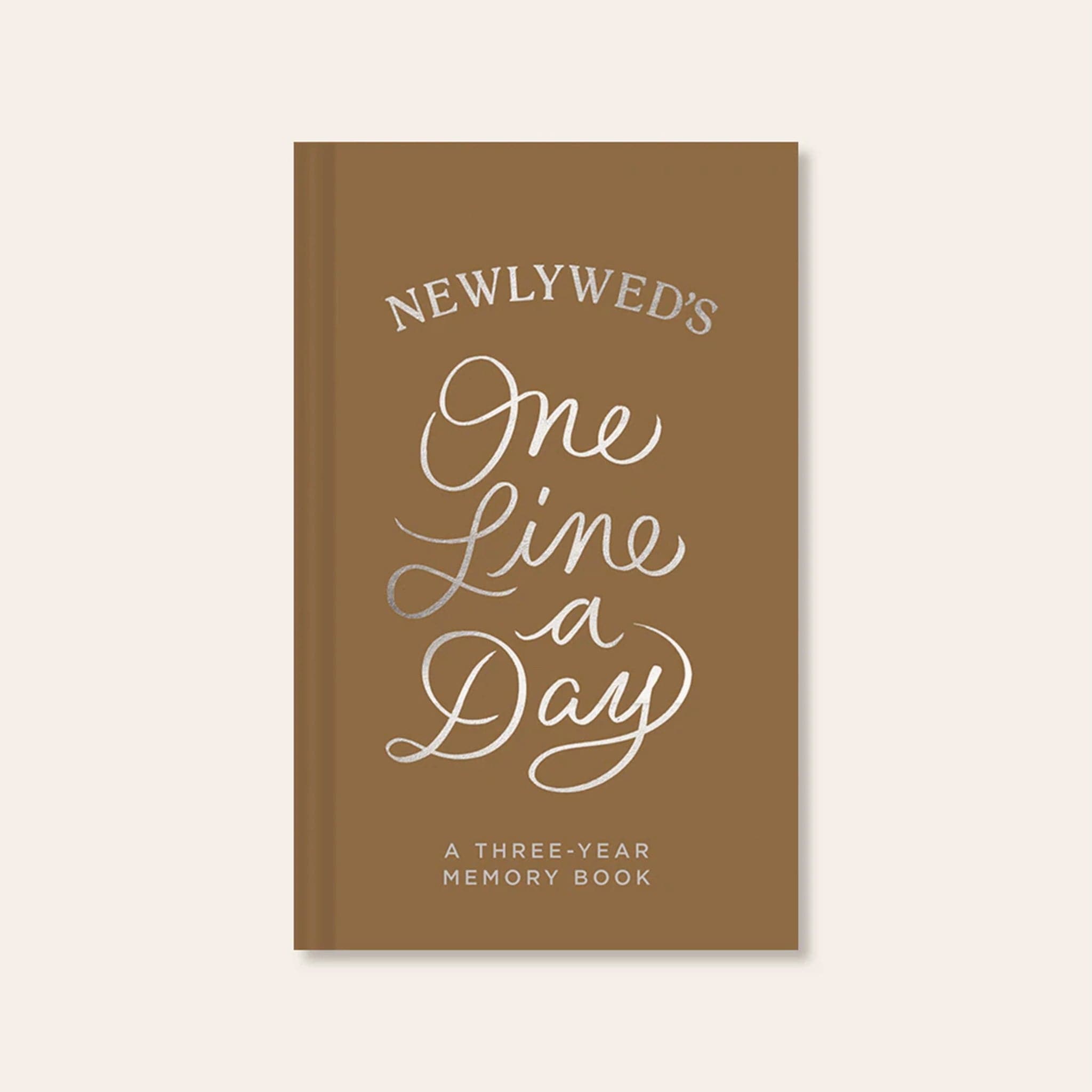 High quality, honey toned memory book reading &#39;Newlywed&#39;s one line a day; a three year memory book&#39; in silver foil lettering across the padded cover.