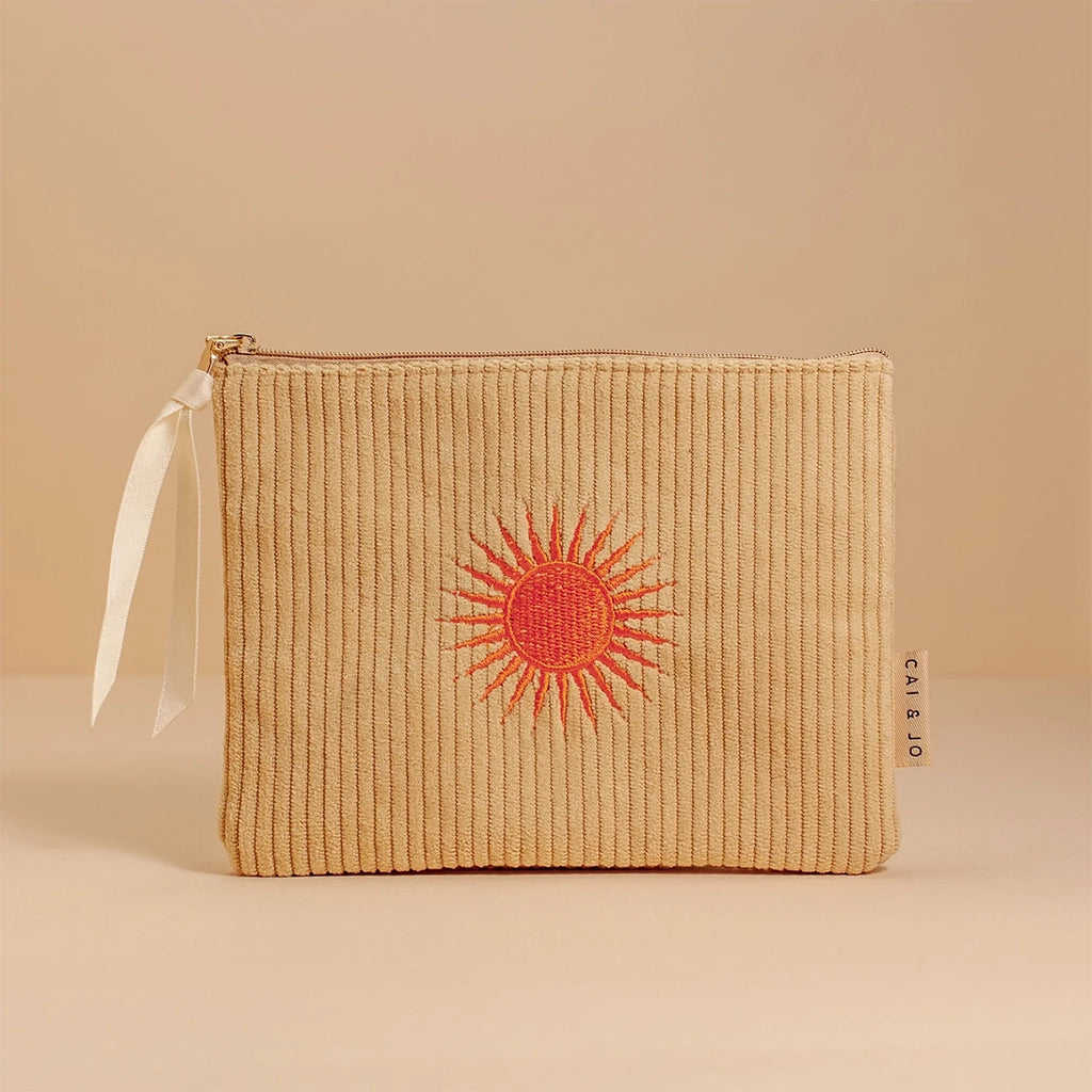 A pastel green corduroy pouch with an orange sun design in the center along with a single zipper going across the top that is detailed with a white ribbon.