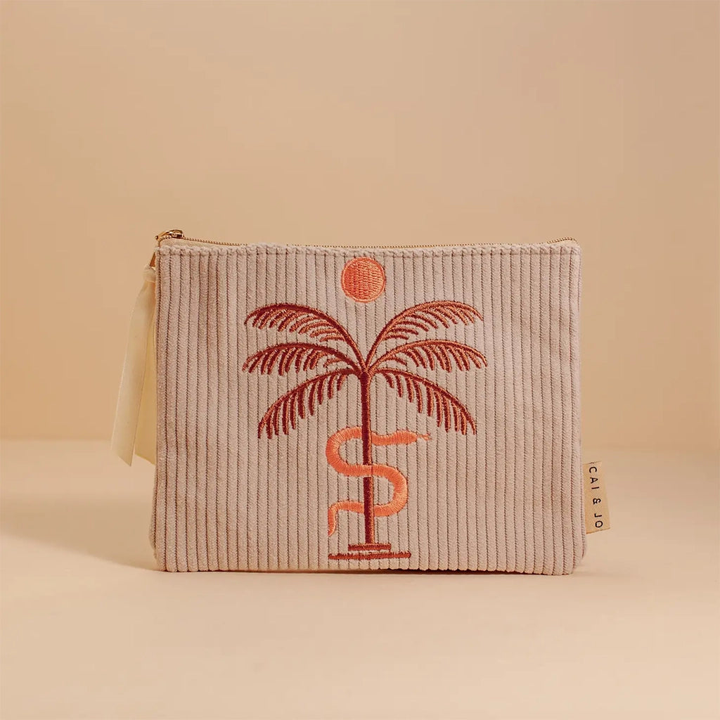 A greyish tan corduroy pouch with a single zipper going across the top and a palm tree, snake and sun graphic in the center.