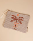 A greyish tan corduroy pouch with a single zipper going across the top and a palm tree, snake and sun graphic in the center.