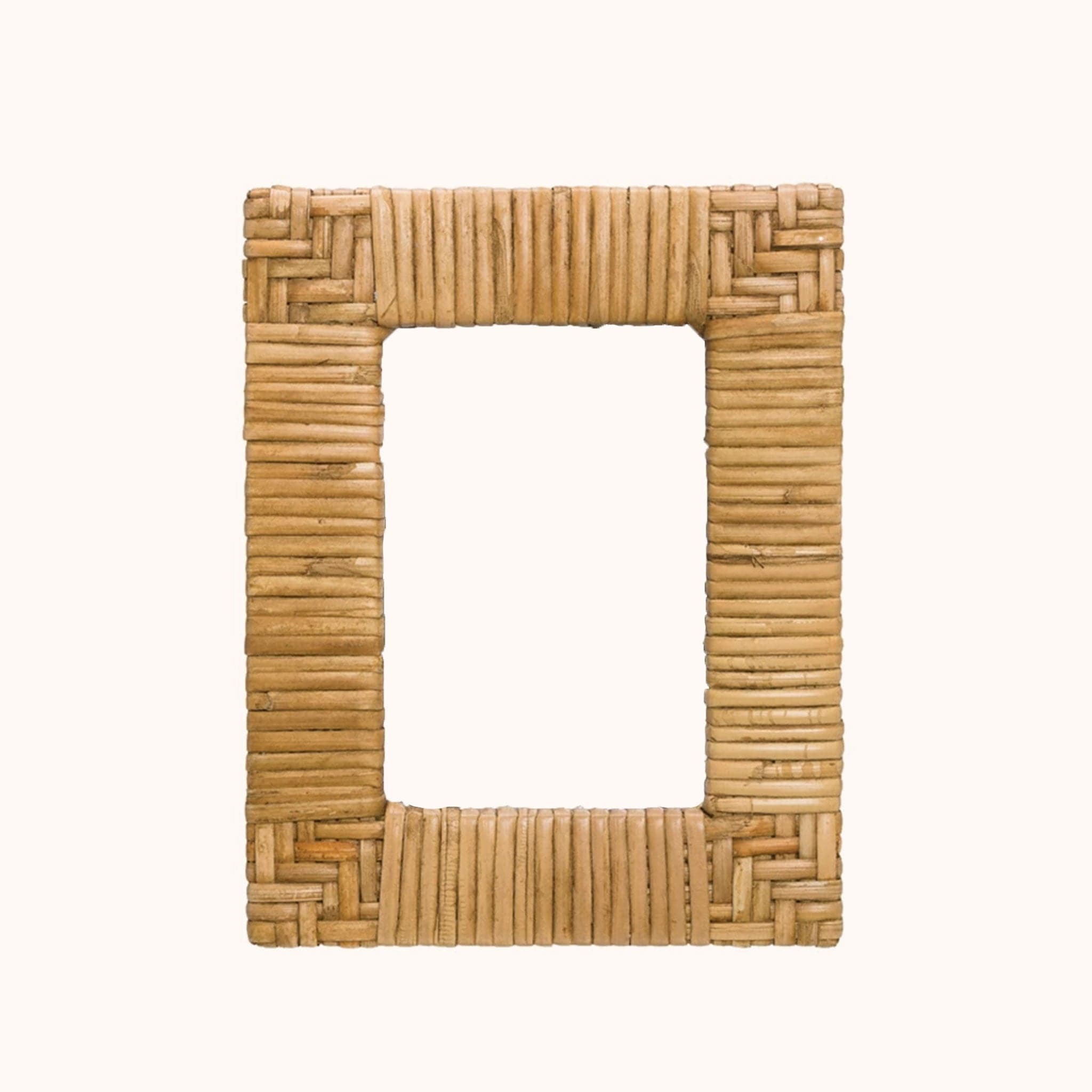 In front of a white background is a rattan picture frame. The corners of the picture frame are a chevron design and the sides are stripes. 