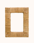 In front of a white background is a rattan picture frame. The corners of the picture frame are a chevron design and the sides are stripes.