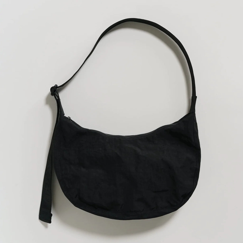 A nylon crescent shoulder bag with an adjustable strap and a single zipper. The interior also features a zipper for optimal organization. 