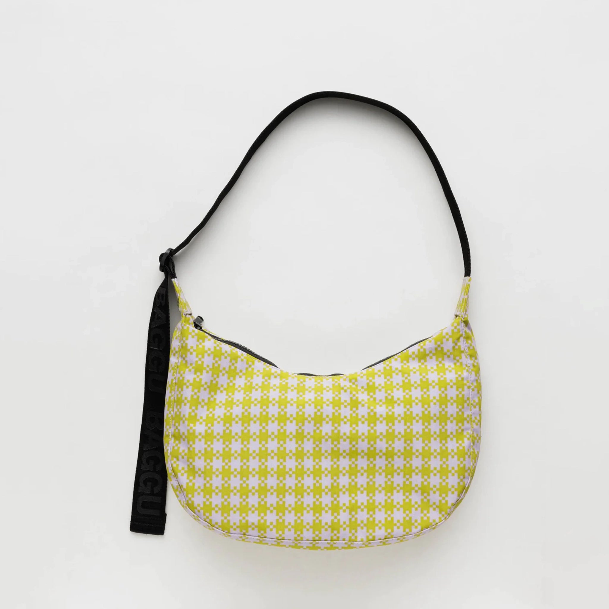 A light pink and lime green gingham nylon crescent shaped bag with an adjustable black strap that reads, &quot;BAGGU&quot; in black and a single zipper.