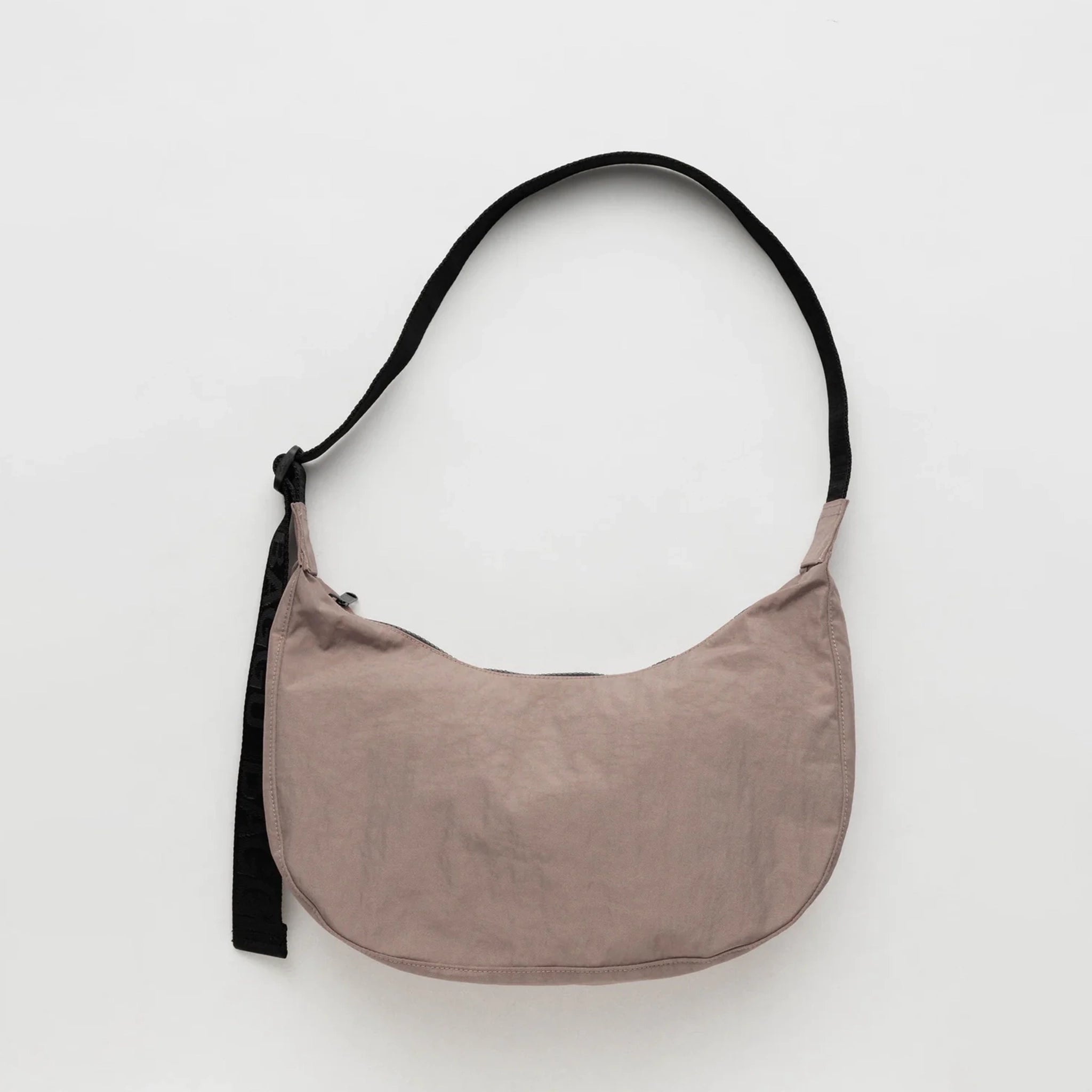 A taupe nylon crescent shaped bag with an adjustable black strap and a single zipper.