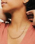 Woman modeling the Aya Necklace, a gold two chain necklace with a thin chain and big chain.