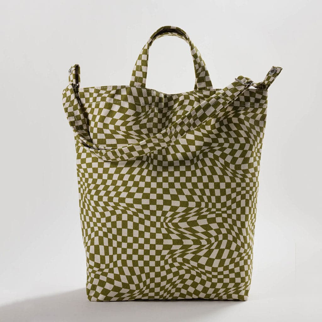 This canvas tote is vertically shaped and filled with a disoriented, trippy moss checkered pattern. The bag is complete with both two smaller handles and one large shoulder strap, both covered in the same pattern. 