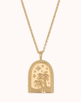 In front of a white background is a gold chain necklace with a gold pendant at the bottom. The pendant has an arched top and straight across bottom. On the front is gold waves and two gold palm trees. Above the trees are gold stars.