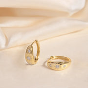 Gold huggie hoop earrings with edged starbursts with three CZ stones along the front.