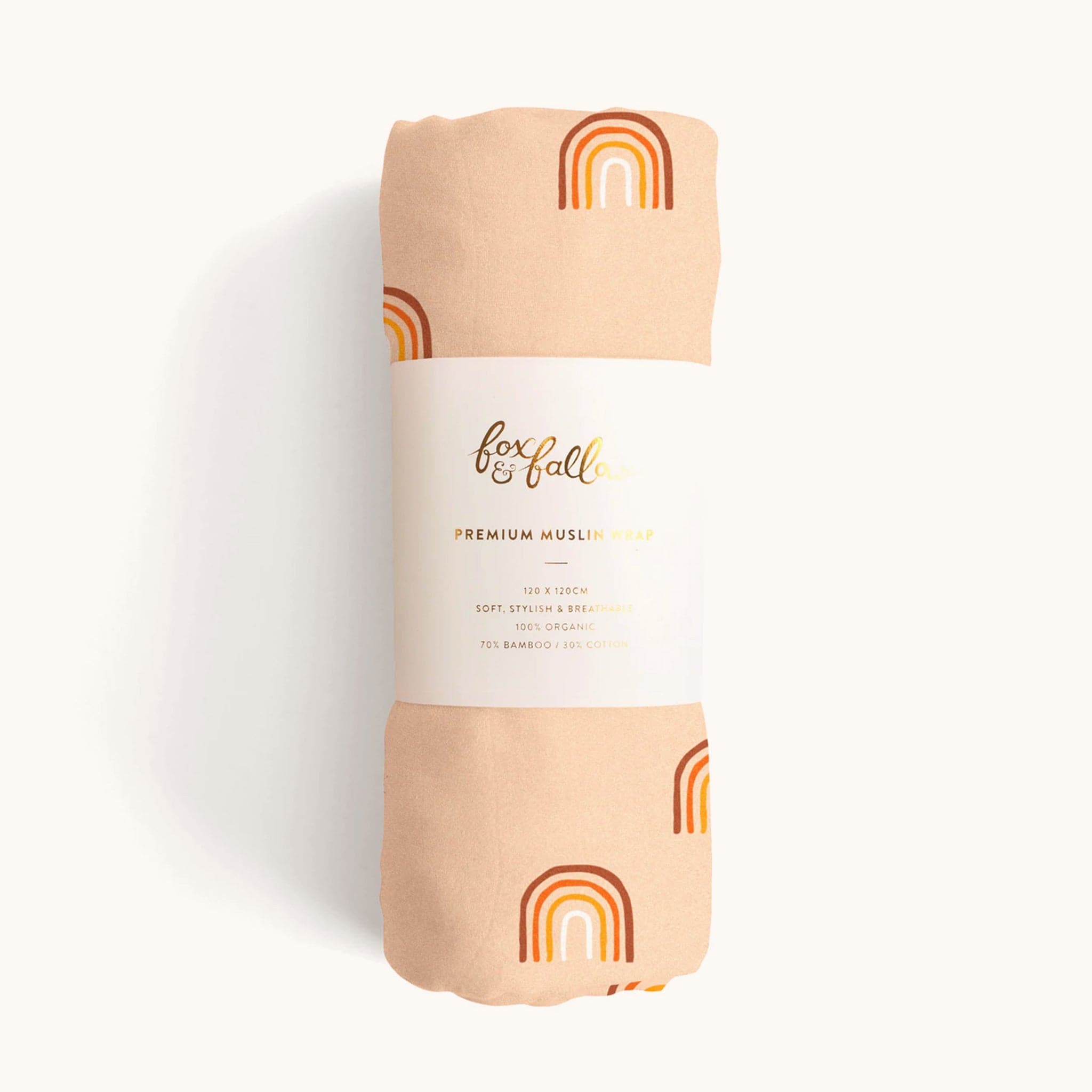 Peach swaddle covered in a warm toned rainbow pattern wrapped in white packaging that reads &#39;fox and follow, premium muslim wrap&#39; in gold foil text. 