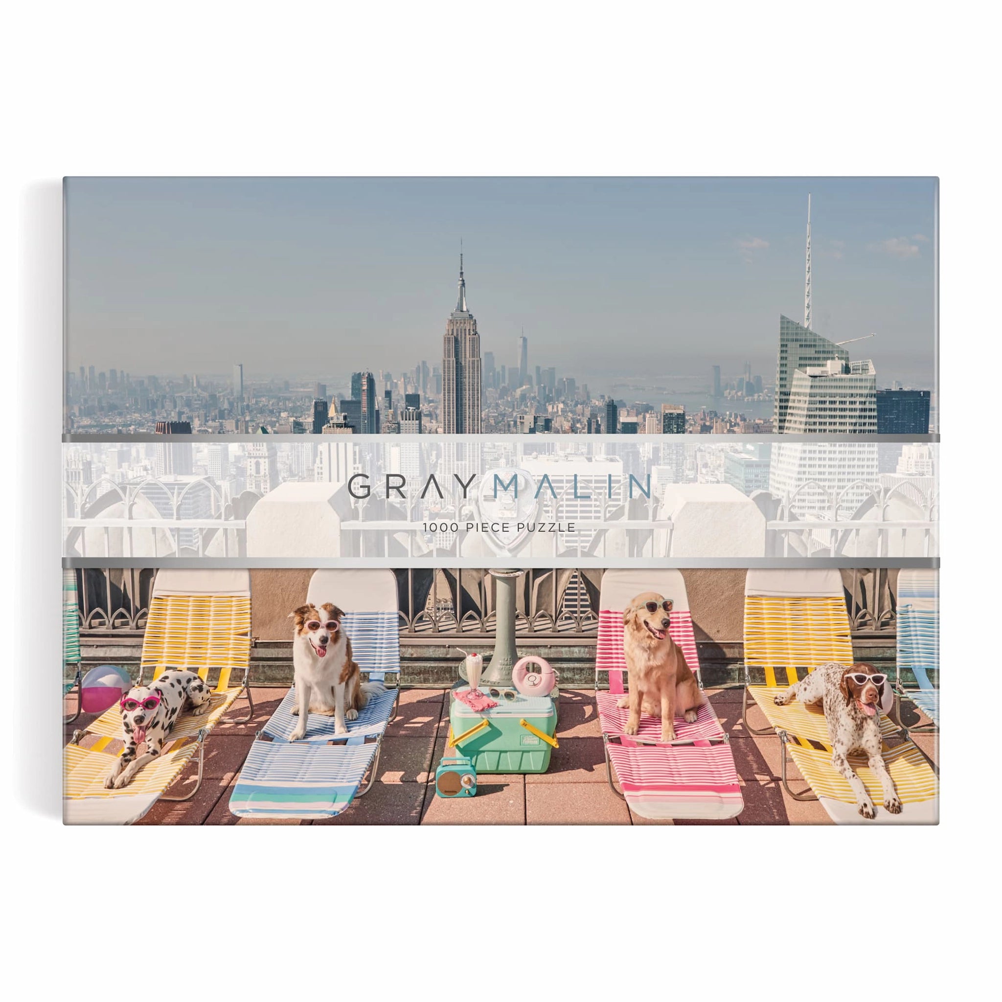 A puzzle in a box with a photograph of New York City with different breeds of dogs wearing sunglasses and sitting on a rooftop on sun chairs.