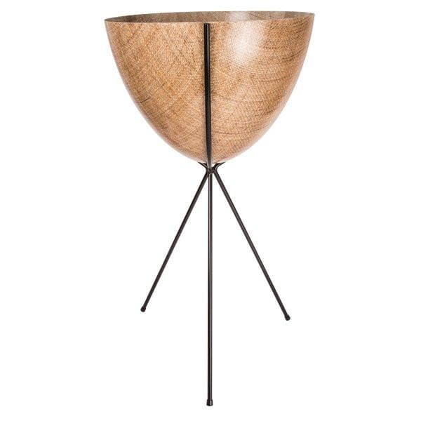 In front of a white background is a wood colored bullet planter. The planter has a wide top and narrows at the bottom. The planter is held up by a black metal stand. The stand has three black metal legs.