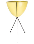 In front of a white background is a yellow colored bullet planter. The planter has a wide top and narrows at the bottom. The planter is held up by a black metal stand. The stand has three black metal legs.