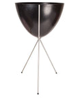 In front of a white background is a black colored bullet planter. The planter has a wide top and narrows at the bottom. The planter is held up by a silver metal stand. The stand has three silver metal legs.