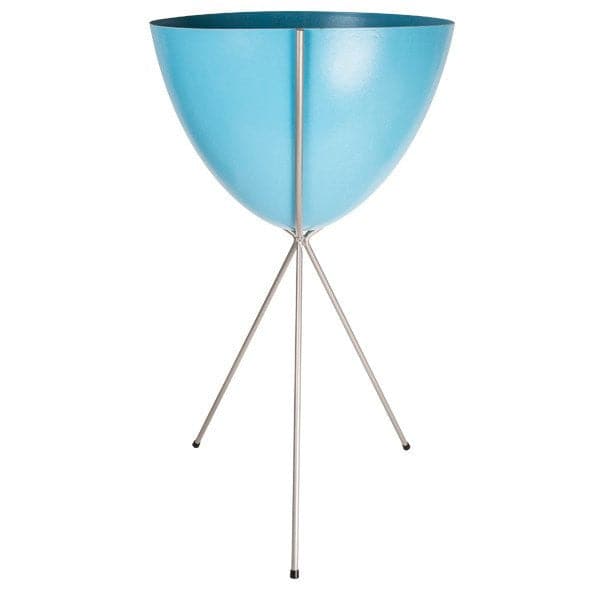 In front of a white background is a bright blue colored bullet planter. The planter has a wide top and narrows at the bottom. The planter is held up by a silver metal stand. The stand has three silver metal legs.