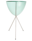 In front of a white background is a turquoise colored bullet planter. The planter has a wide top and narrows at the bottom. The planter is held up by a silver metal stand. The stand has three silver metal legs.