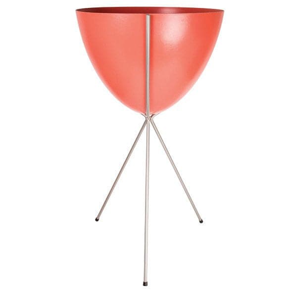 In front of a white background is a red colored bullet planter. The planter has a wide top and narrows at the bottom. The planter is held up by a silver metal stand. The stand has three silver metal legs.