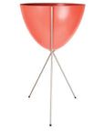 In front of a white background is a red colored bullet planter. The planter has a wide top and narrows at the bottom. The planter is held up by a silver metal stand. The stand has three silver metal legs.