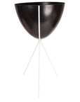 In front of a white background is a black colored bullet planter. The planter has a wide top and narrows at the bottom. The planter is held up by a white metal stand. The stand has three white metal legs.