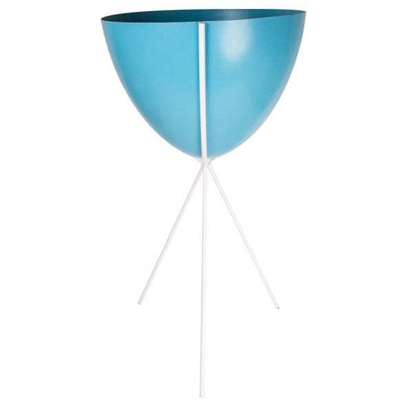 In front of a white background is a blue colored bullet planter. The planter has a wide top and narrows at the bottom. The planter is held up by a white metal stand. The stand has three white metal legs.