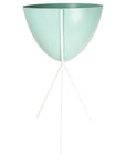In front of a white background is a turquoise colored bullet planter. The planter has a wide top and narrows at the bottom. The planter is held up by a white metal stand. The stand has three white metal legs.