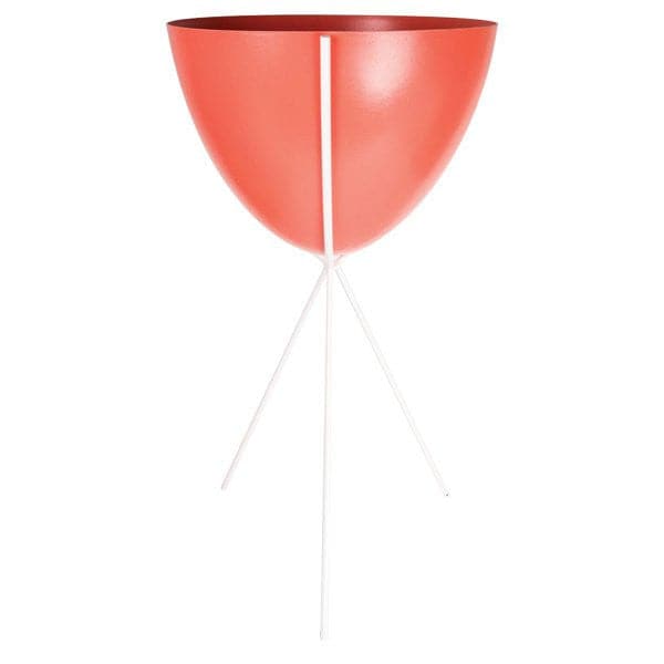 In front of a white background is a red colored bullet planter. The planter has a wide top and narrows at the bottom. The planter is held up by a white metal stand. The stand has three white metal legs.
