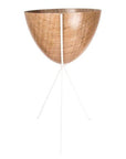 In front of a white background is a wood colored bullet planter. The planter has a wide top and narrows at the bottom. The planter is held up by a white metal stand. The stand has three white metal legs.