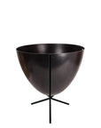 In front of white background is a black planter in a short black metal stand. The bullet planter is wide at the top and narrow at the bottom. The metal stand has three legs.