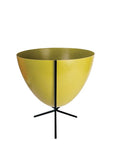 In front of white background is an olive green planter in a short black metal stand. The bullet planter is wide at the top and narrow at the bottom. The metal stand has three legs.