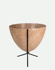 In front of white background is a wood colored planter in a short black metal stand. The bullet planter is wide at the top and narrow at the bottom. The metal stand has three legs.