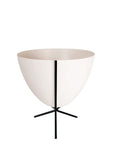 In front of white background is a white planter in a short black metal stand. The bullet planter is wide at the top and narrow at the bottom. The metal stand has three legs.