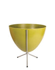 In front of white background is an olive green planter in a short silver metal stand. The bullet planter is wide at the top and narrow at the bottom. The metal stand has three legs.