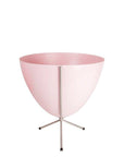 In front of white background is a pink planter in a short silver metal stand. The bullet planter is wide at the top and narrow at the bottom. The metal stand has three legs.