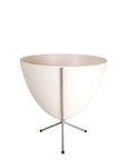In front of white background is a white planter in a short silver metal stand. The bullet planter is wide at the top and narrow at the bottom. The metal stand has three legs.