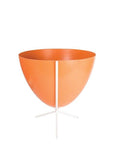 In front of white background is an orange planter in a short white metal stand. The bullet planter is wide at the top and narrow at the bottom. The metal stand has three legs.