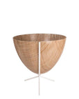 In front of white background is a wood colored bullet planter in a short white metal stand. The bullet planter is wide at the top and narrow at the bottom. The metal stand has three legs.