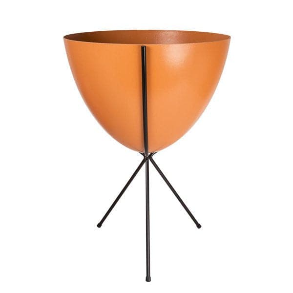 In front of white background is an orange planter in a black metal stand. The bullet planter is wide at the top and narrow at the bottom. The metal stand has three legs. 