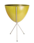 In front of white background is an olive green planter in a silver metal stand. The bullet planter is wide at the top and narrow at the bottom. The metal stand has three legs.