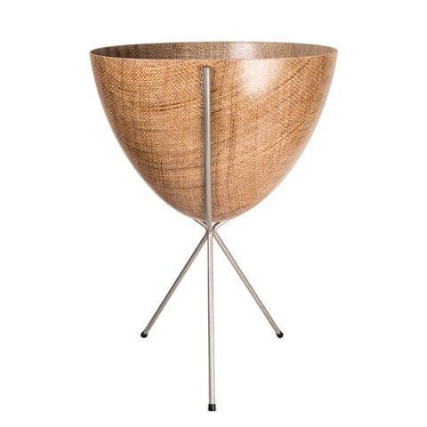 In front of white background is a wood colored planter in a silver metal stand. The bullet planter is wide at the top and narrow at the bottom. The metal stand has three legs. 