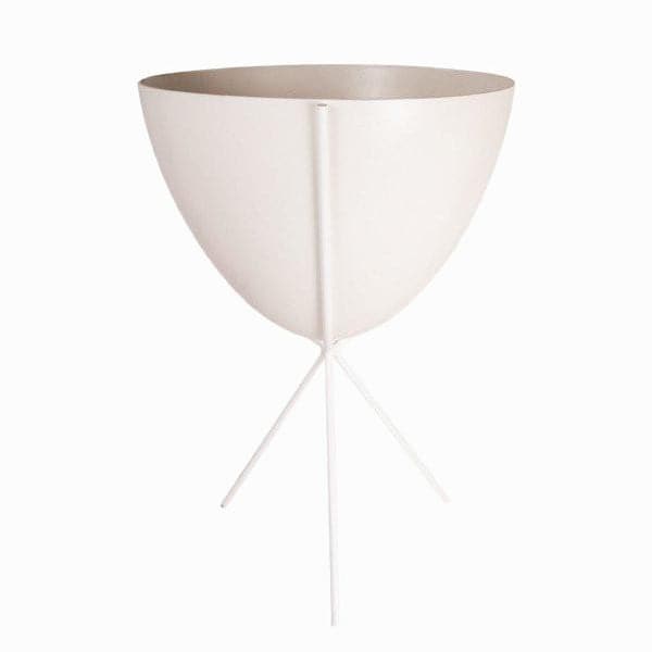 In front of white background is a white planter in a white metal stand. The bullet planter is wide at the top and narrow at the bottom. The metal stand has three legs.
