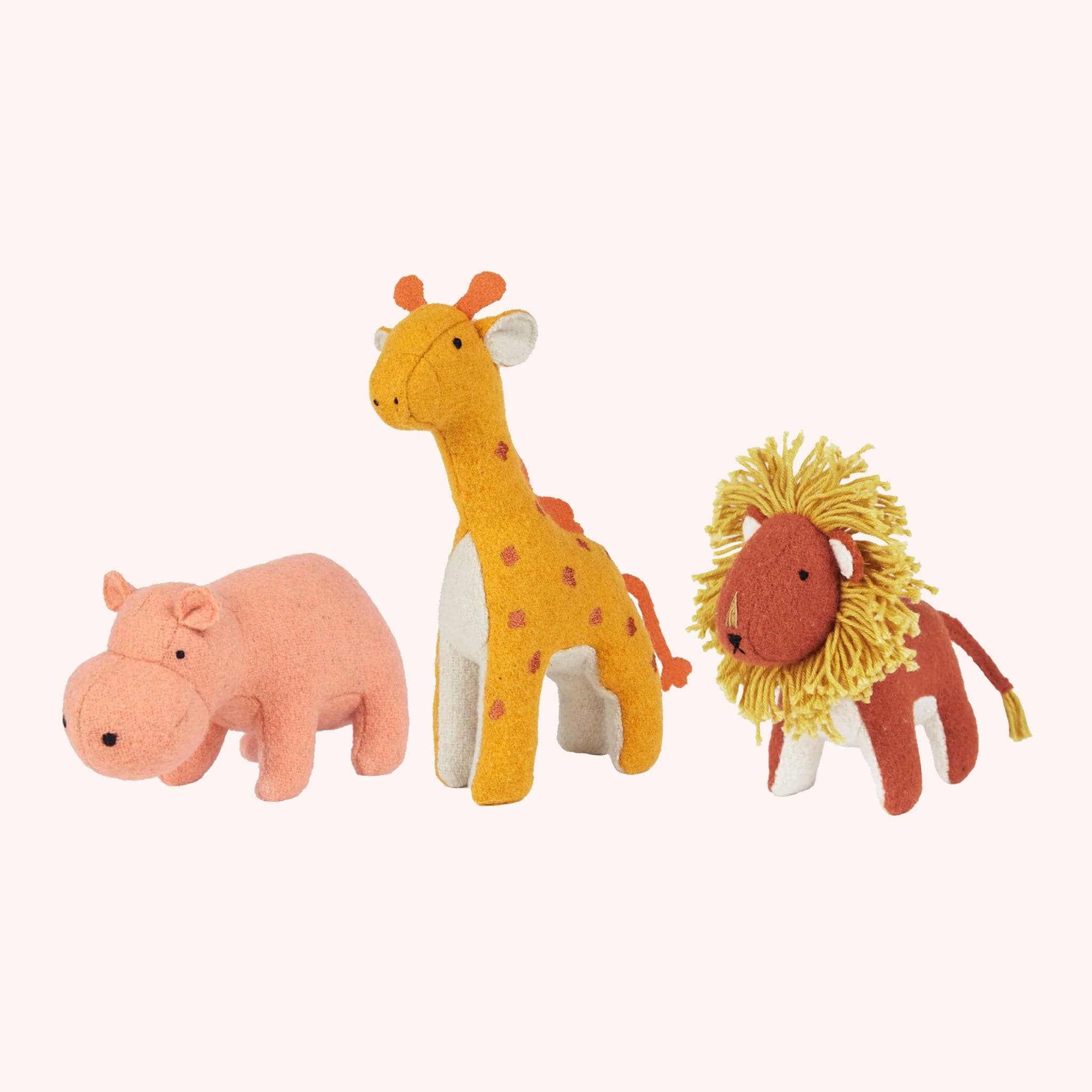 A stuffed animal set inspired by the Savannah. It includes a pink hippo, a red lion with a yellow mane, and a mustard yellow giraffe with orange spots and an orange tail.