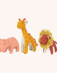 A stuffed animal set inspired by the Savannah. It includes a pink hippo, a red lion with a yellow mane, and a mustard yellow giraffe with orange spots and an orange tail.